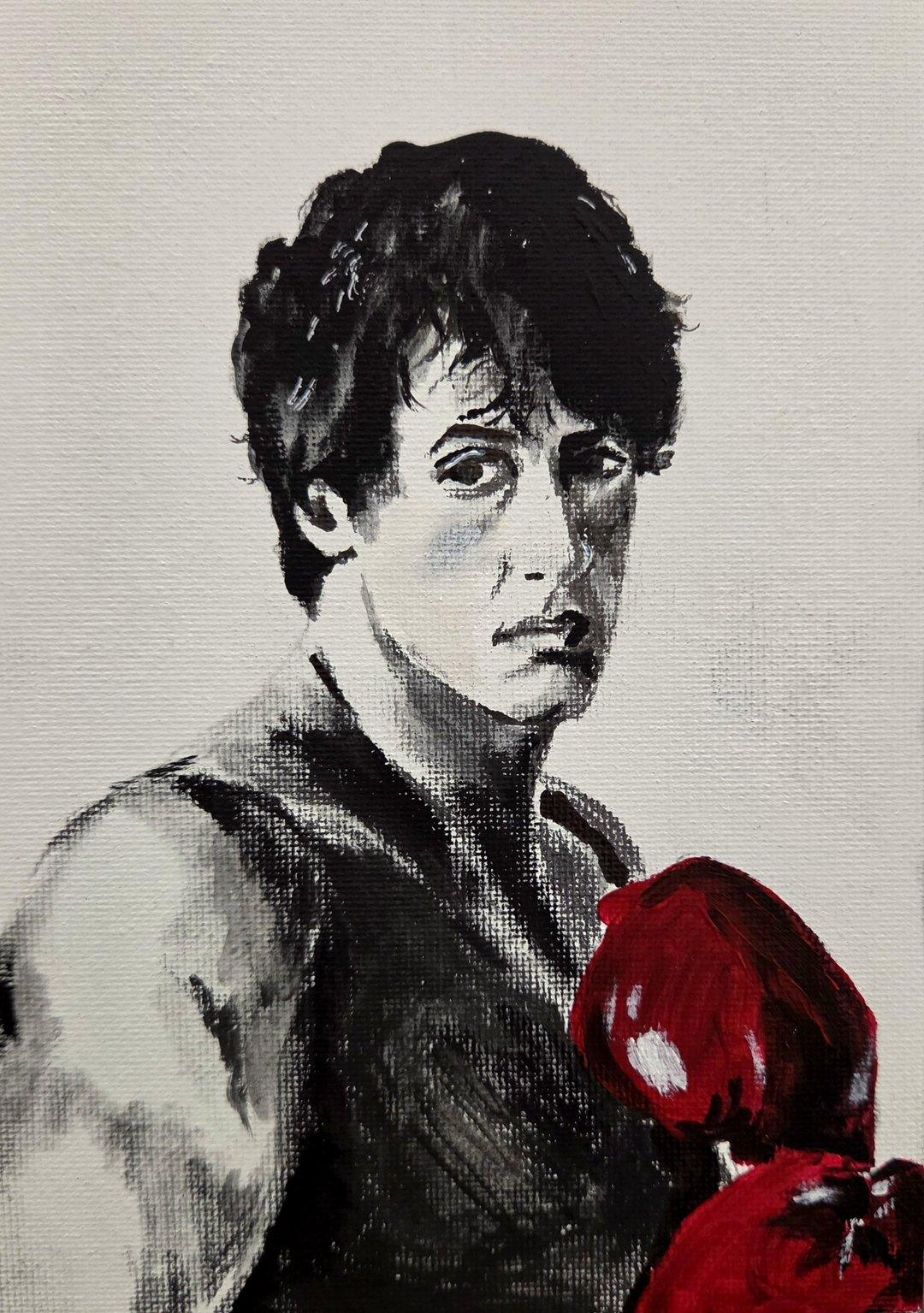Black-and-white portrait of a boxer with dark curly hair, his red boxing gloves the only color in the painting.